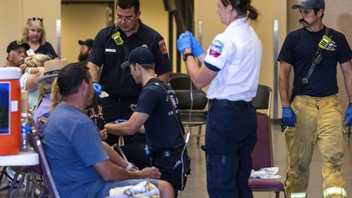 Members of the Colorado Springs Fire Department and AMR paramedics treat people for heat-related illness at the Pikes Peak Regional Airshow on Saturday, Aug. 17, 2024 in Colorado Springs, Colo. (Parker Seibold/The Gazette via AP)