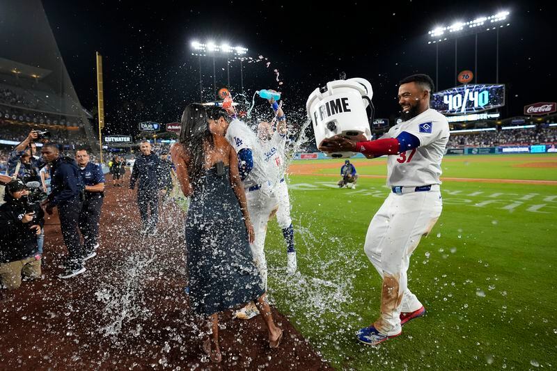 Los Angeles Dodgers' Teoscar Hernández (37) dumps water on designated hitter Shohei Ohtani (17) after Ohtani hit a grand slam during the eighth inning of a baseball game against the Tampa Bay Rays in Los Angeles, Friday, Aug. 23, 2024. Will Smith, Tommy Edman, and Max Muncy also scored. The Dodgers won 7-3. (AP Photo/Ashley Landis)