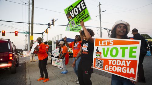 Volunteers encourage citizens to vote on Tuesday across the street from the Metropolitan Library in Atlanta. CHRISTINA MATACOTTA FOR THE ATLANTA JOURNAL-CONSTITUTION.