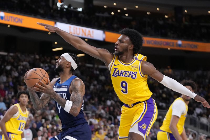 Minnesota Timberwolves guard Nickeil Alexander-Walker, center, shoots as Los Angeles Lakers guard Bronny James, right, defends during the first half of a preseason NBA basketball game, Friday, Oct. 4, 2024, in Palm Desert, Calif. (AP Photo/Mark J. Terrill)