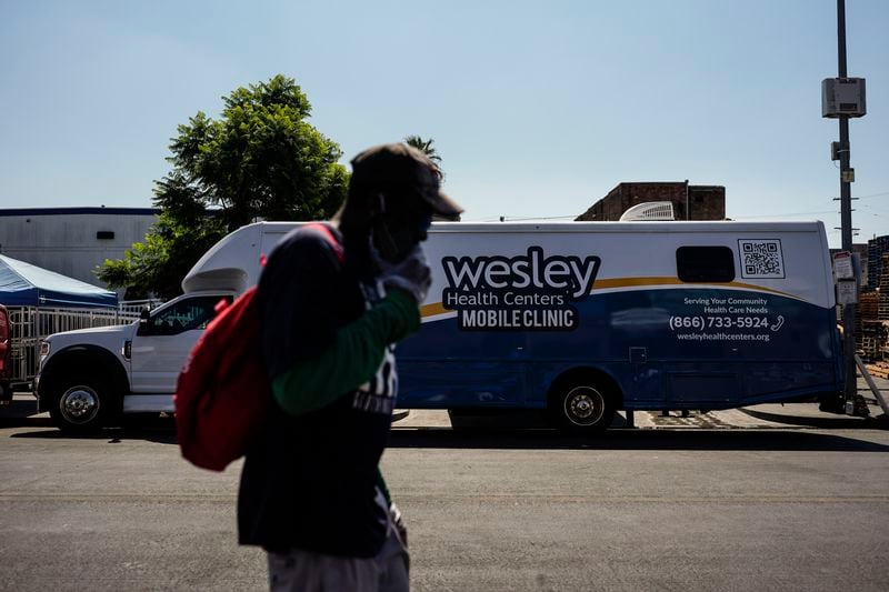 A homeless person walks past Wesley Health Centers' mobile clinic in the Skid Row area of Los Angeles, Tuesday, Aug. 27, 2024. (AP Photo/Jae C. Hong)