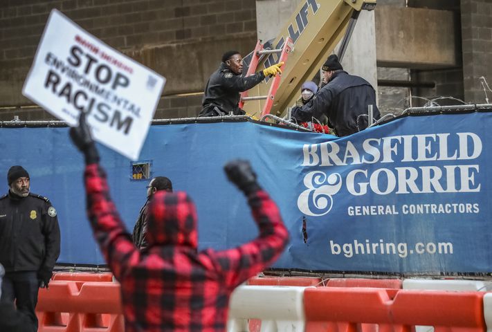 Two people locked themselves to construction equipment in Midtown to protest Atlanta’s planned public safety training center, causing a street to close amid the Monday morning commute, Jan. 29, 2024. The activists used reinforced bindings to lock their arms around the equipment at a Brasfield & Gorrie work site at 12th and Juniper streets. One person was locked to a construction elevator and the other to a boom. Both were released by 10:15 a.m. Juniper Street was closed to traffic for hours Monday morning before reopening around 11:30 a.m. SWAT team members were also at the scene for assistance in cutting the activists free. Brasfield & Gorrie is one of the contractors hired to build the training facility at the site of the old Atlanta Prison Farm in the south DeKalb County woods. Those opposed to the facility say its construction will damage the South River Forest and contribute to what they say is the militarization of the police department. (John Spink / John.Spink@ajc.com)

