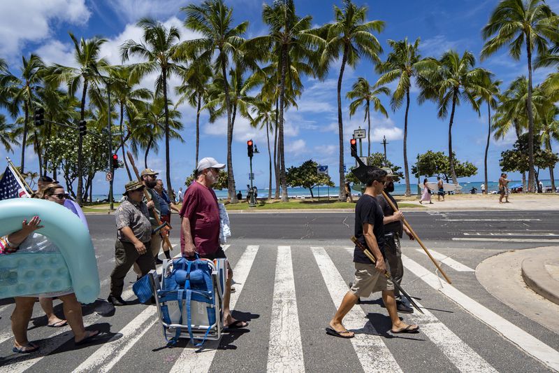 Members of Hawaii Firearms Coalition walk around Waikiki with their non-firearm weapons on Saturday, June 22, 2024, in Honolulu, Hawaii. (AP Photo/Mengshin Lin)