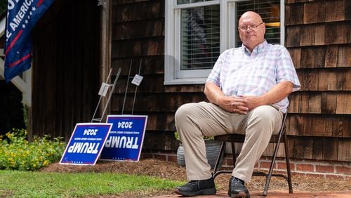 The Rev. Brant Kennedy, the first vice chair of the Washington County Republican Party, poses for a portrait in front of his home in Sandersville. Trump signs lean on a wall for local Republicans to pick up. (Seeger Gray / AJC)