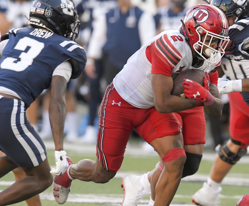 Utah running back Micah Bernard (2) carries the ball as Utah State cornerback JD Drew (3) pursues in the second half of an NCAA college football game Saturday, Sept. 14, 2024, in Logan, Utah. (Eli Lucero/The Herald Journal via AP)