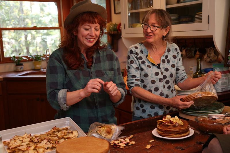 Ashley Capps (left) and Barbara Swell decorate an apple stack cake at Swell’s home in Asheville, N.C. TYSON HORNE / TYSON.HORNE@AJC.COM