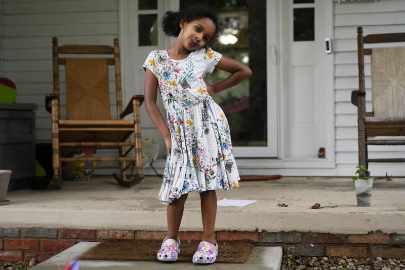 Lily Tolley, 6, poses for a photo on her front porch on Wednesday, June 5, 2024, in Springfield, Ill. She can tell the difference between the mute females and noisy males, what the cicada parts are and how it feels "a little prickly" when a cicada walks on you. (AP Photo/Carolyn Kaster)