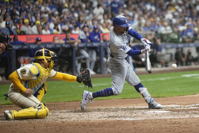 Los Angeles Dodgers' Mookie Betts, right, hits an RBI single during the seventh inning of a baseball game against the Milwaukee Brewers, Monday, Aug. 12, 2024, in Milwaukee. (AP Photo/Aaron Gash)