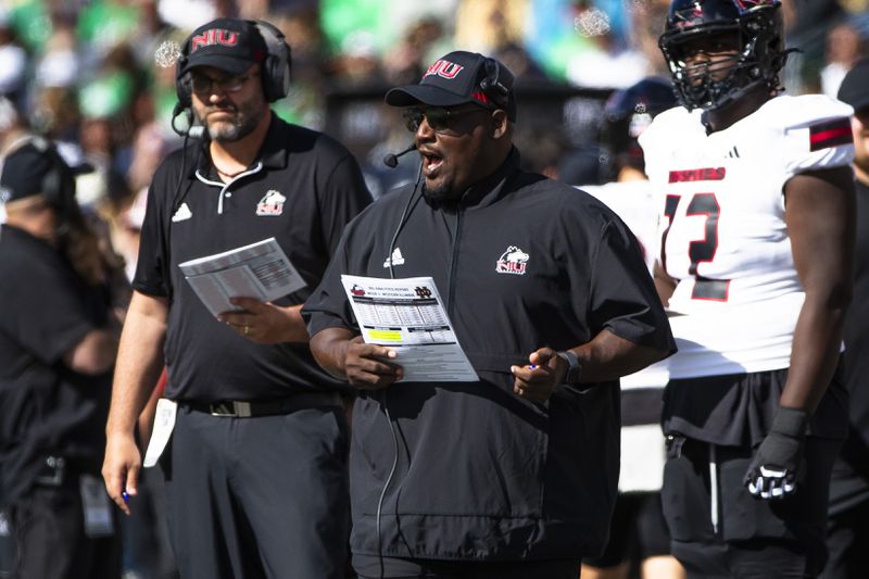 Northern Illinois head coach Thomas Hammock, center, talks into his headset during an NCAA college football game against Notre Dame, Saturday, Sept. 7, 2024, in South Bend, Ind. (AP Photo/Michael Caterina)