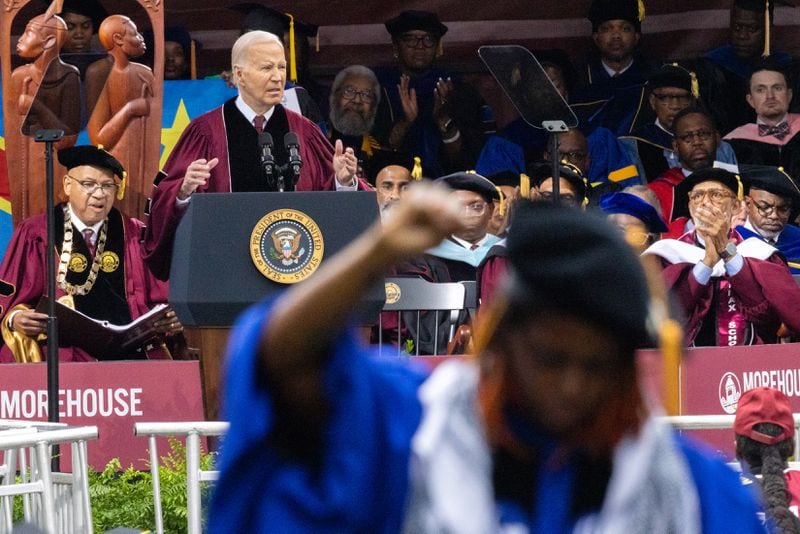 President Joe Biden speaks at the commencement ceremony on May 19, 2024 at Morehouse College as assistant professor Taura Taylor raises her fist in protest of the Gaza war. (Arvin Temkar / AJC)