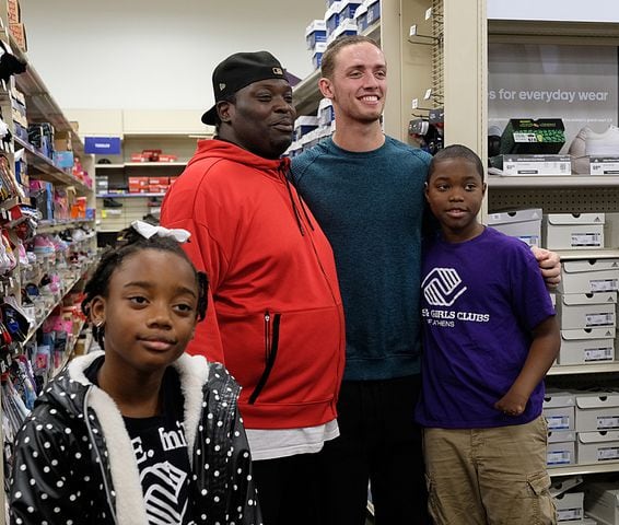 Kendyal Freeman, 8, Darius Ollie and JÕLyn Ollie, 11 pose with UGA quarterback Carson Beck on a shopping spree at Academy. Carson Beck was on site at an Athens Academy store Sunday December 17, 2023, to give out gift cards to lucky members of area Boys and Girls Clubs. Academy contributed $200 for each child and he kicked in $135 more of his own money to help families out. 

credit: Nell Carroll for the AJC
