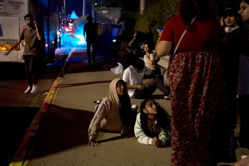 Israelis wait to re-board their bus after projectiles were launched from Iran are being intercepted in the skies over in Rosh HaAyin, Israel, Tuesday, Oct. 1, 2024. (AP Photo/Maya Alleruzzo)