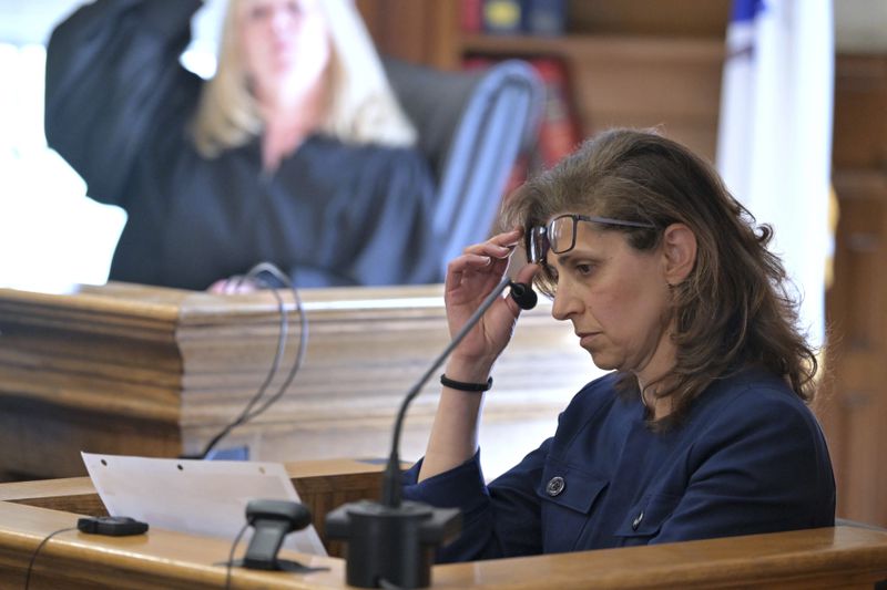 Dr. Irini Scordi-Bello, a medical examiner for the state's medical examiner's office looks at an autopsy photo of John O'Keefe during her testimony in Karen Read's trial in Norfolk Superior Court, Friday, June 21, 2024, in Dedham, Mass. Read, 44, is accused of running into her Boston police officer boyfriend with her SUV in the middle of a nor'easter and leaving him for dead after a night of heavy drinking. (AP Photo/Josh Reynolds, Pool)