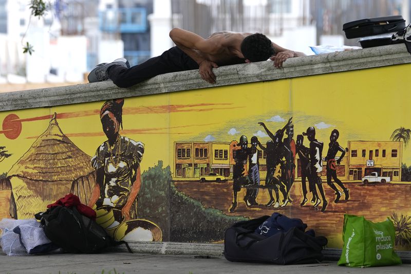 A homeless man who goes by the name of CJ lies on top of a brick wall on the first day of a statute that took effect, making it illegal in Florida to sleep on sidewalks, in parks, on beaches or in other public spaces — one of the country's strictest anti-homelessness laws, Tuesday, Oct. 1, 2024, in Fort Lauderdale, Fla. (AP Photo/Lynne Sladky)