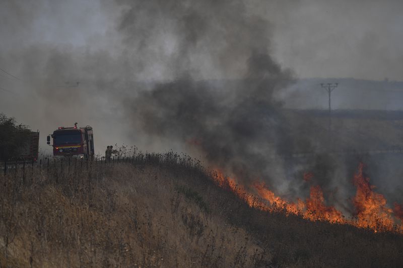 Firefighters work to extinguish a fire following an attack from Lebanese Hezbollah group, in an area in the Israeli-controlled Golan Heights, Thursday, July 4, 2024. The attack by the Iran-backed militant group on Thursday was one of the largest in the monthslong conflict along the Lebanon-Israel border, with tensions boiling in recent weeks. (AP Photo/Gil Eliyahu)