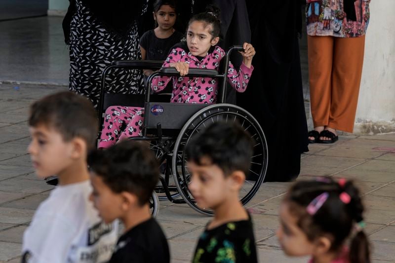 Zahraa on a wheel chair looks on as volunteers of the Russian Cultural Center entertain displaced children at a school in Beirut, Lebanon, Thursday, Oct. 3, 2024, after fleeing the Israeli airstrikes in the south. (AP Photo/Bilal Hussein)