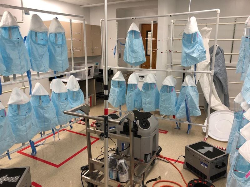 Protective hoods hang from racks at Emory University Hospital during a sterilization cycle using vaporized hydrogen peroxide. Emory is piloting a decontamination program to extend the life of single-use protective gear. SPECIAL TO THE AJC