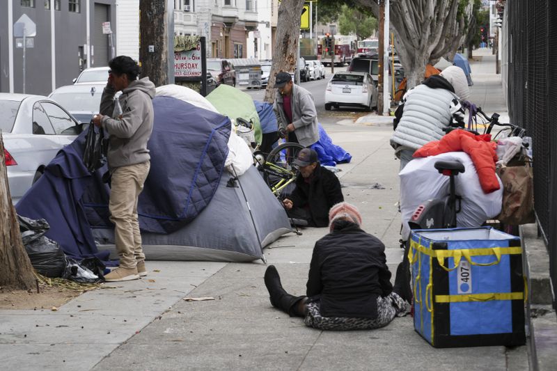 Homeless people gather with their belongings and tents in the Mission District, Tuesday, Sept. 10, 2024, in San Francisco. (AP Photo/Terry Chea)