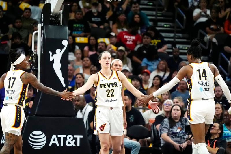 Indiana Fever guard Caitlin Clark (22) is congratulated by Fever guard Erica Wheeler (17) and Fever center Temi Fagbenle (14) after scoring against the Phoenix Mercury during the first half of a WNBA basketball game, Sunday, June 30, 2024, in Phoenix. (AP Photo/Ross D. Franklin)