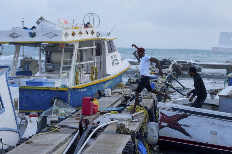 A fisherman jumps from a vessel damaged by Hurricane Beryl at the Bridgetown Fisheries in Barbados, Monday, July 1, 2024. (AP Photo/Ricardo Mazalan)