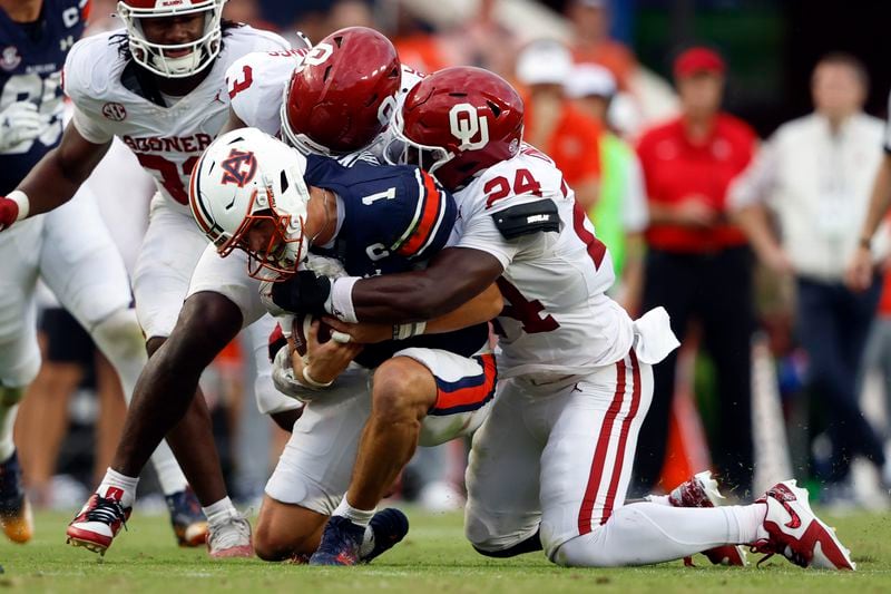 Auburn quarterback Payton Thorne (1) is tackled by Oklahoma defensive back Robert Spears-Jennings (3) and linebacker Samuel Omosigho (24) as he tries to carry the ball during the second half of an NCAA college football game, Saturday, Sept. 28, 2024, in Auburn, Ala. (AP Photo/Butch Dill)