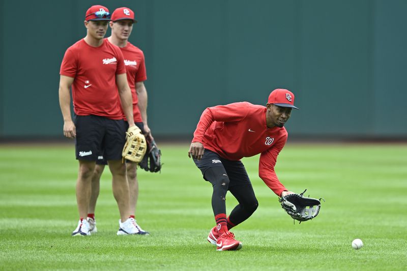 Washington Nationals' Alex Call, left, with Nationals' Jacob Young watch newly arrived teammate from the minor leagues, Darren Baker, right, field a ground ball during outfield practice before a baseball game against the Chicago Cubs, Sunday, Sept. 1, 2024, in Washington. (AP Photo/John McDonnell)