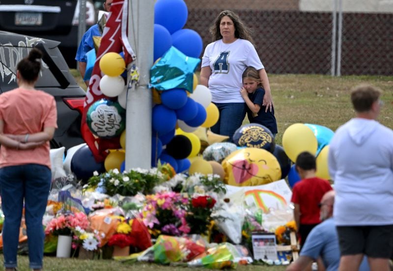 Mourners visit a makeshift memorial at the flagpole at Apalachee High School, where two teachers and two students were killed, and a 14-year-old is charged in their deaths. (Hyosub Shin / AJC)