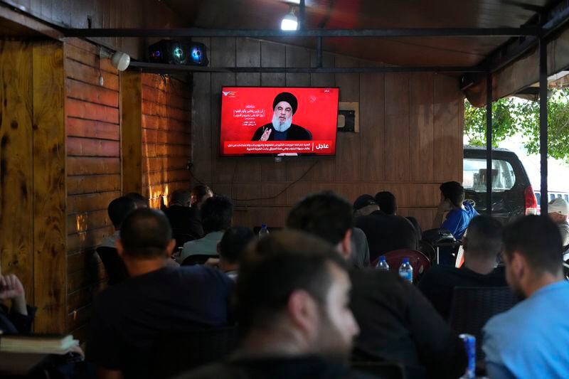 People watch the speech of Hezbollah leader Hassan Nasrallah on a tv screen as they sit in a cafe in the southern suburbs of Beirut, Thursday, Sept. 19, 2024. (AP Photo/Hassan Ammar)