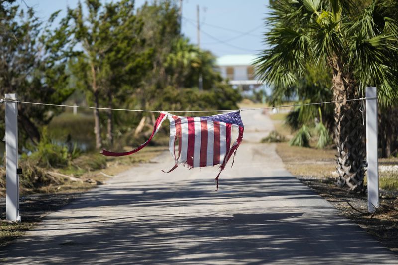 A tattered American flag hangs on a rope on a now closed road in the aftermath of Hurricane Helene, in Jena, Fla., Sunday, Sept. 29, 2024. (AP Photo/Gerald Herbert)