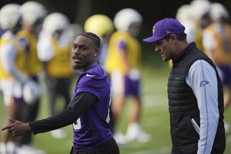 Minnesota Vikings wide receiver Justin Jefferson (18), left, talks to head coach Kevin O'Connell during a practice session at The Grove in Watford, England Friday, Oct. 4, 2024. (AP Photo/Kin Cheung)