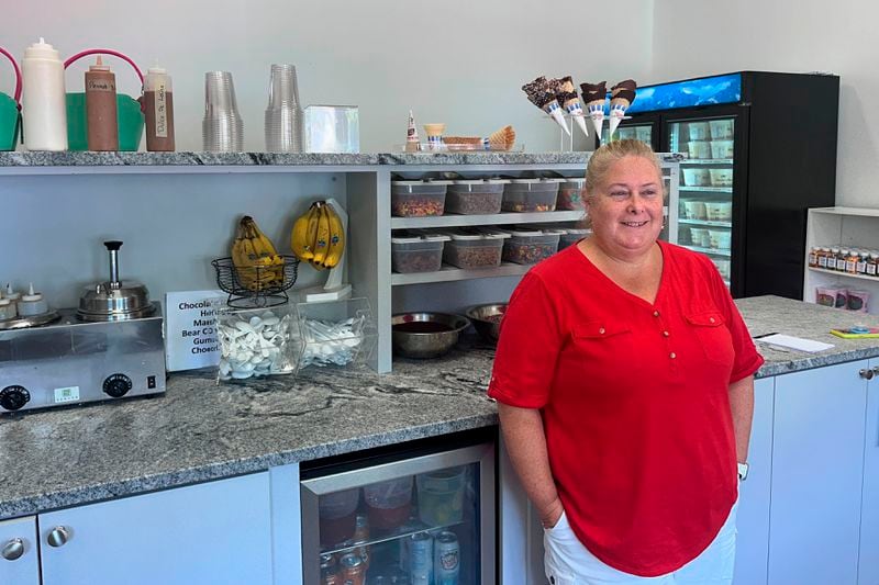 Nancy Thrasher, co-owner of Furlong's Candies & Ice Cream, stands near ice cream and toppings at the store, Wednesday, Aug. 21, 2024, in Norwood, Mass. (AP Photo/Michael Casey)