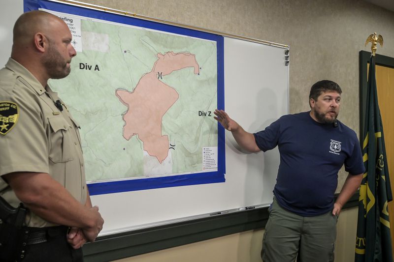 Incident Commander Brandon Sanchez, right, talks about the status of the First Thunder Fire on Wednesday morning along with Pennington County Sheriff's Department Lt. Jason Mitzel, left, during a media briefing at the Mystic Ranger District headquarters in Rapid City, S.D. (Matt Gade/Rapid City Journal via AP)