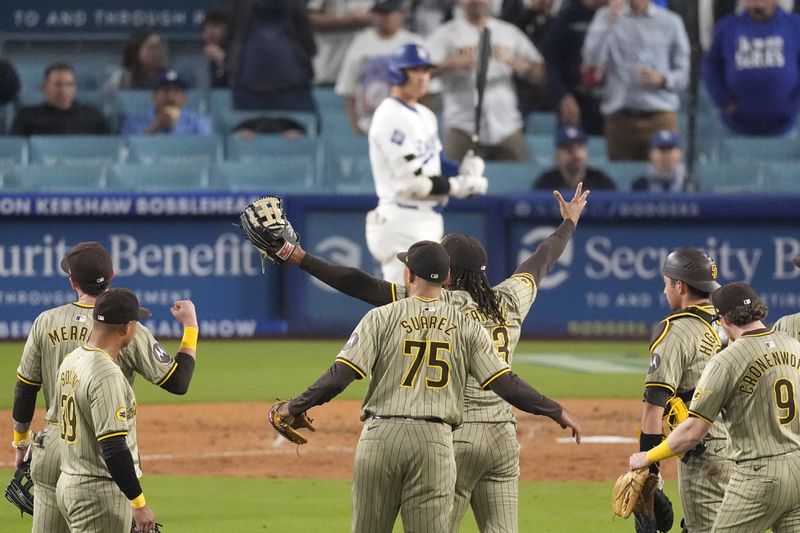 Members of the San Diego Padres celebrate after the Padres clinched a playoff spot with a triple play to end their baseball game as Los Angeles Dodgers' Shohei Ohtani stands at the plate, Tuesday, Sept. 24, 2024, in Los Angeles. (AP Photo/Mark J. Terrill)