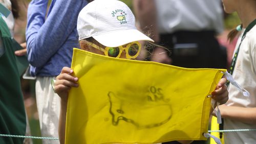 A young golf fan looks at a Masters flag after she received autographs Wednesday.