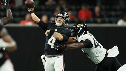 Atlanta Falcons quarterback Taylor Heinicke (4) attempts a pass as he is tackled by Jacksonville Jaguars defensive end Travon Walker (44) during the first half in an preseason NFL football game at Mercedes-Benz Stadium, on Friday, Aug. 23, 2024, in Atlanta. (Jason Getz / AJC)
