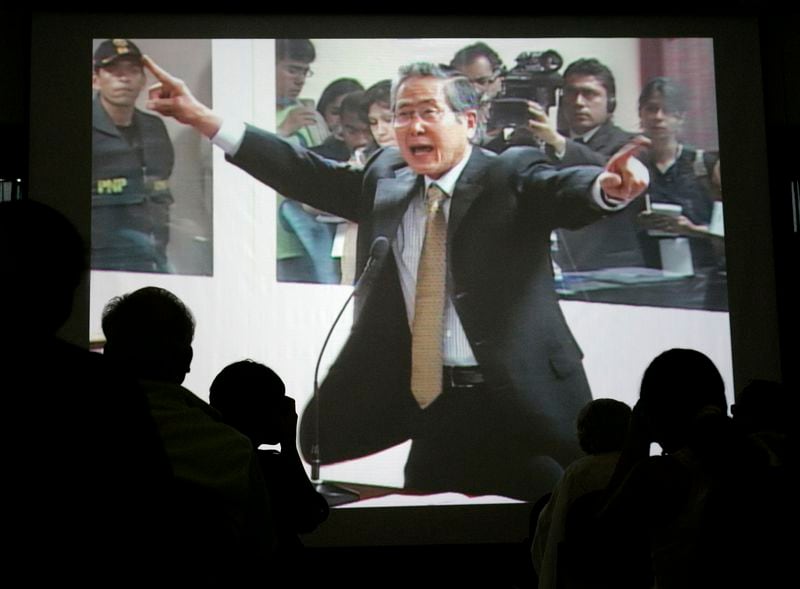 FILE - Peru's former President Alberto Fujimori is seen gesturing on a screen during the first day of his trial on charges of alleged human rights violations and corruption during his government at a police base in Lima, Dec. 10, 2007. (AP Photo/Martin Mejia, File)