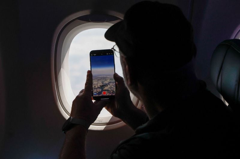 A passenger takes photos while waiting for the solar eclipse to begin on the flight from Dallas Fort Worth International Airport to Detroit Metro Airport on Monday, April 8, 2024. (Natrice Miller/ AJC)