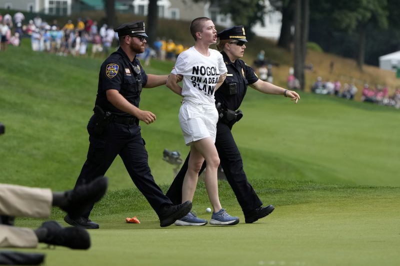 Protesters are led away after they ran onto the course on at the 18th hole during the final round of the Travelers Championship golf tournament at TPC River Highlands, Sunday, June 23, 2024, in Cromwell, Conn. (AP Photo/Seth Wenig)
