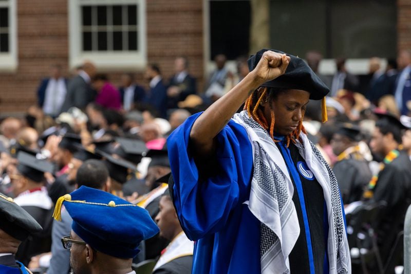 Assistant Professor Taura Taylor raises her fist in protest of the Gaza war at the Morehouse commencement ceremony in Atlanta on Sunday, May 19, 2024. (Arvin Temkar / AJC)