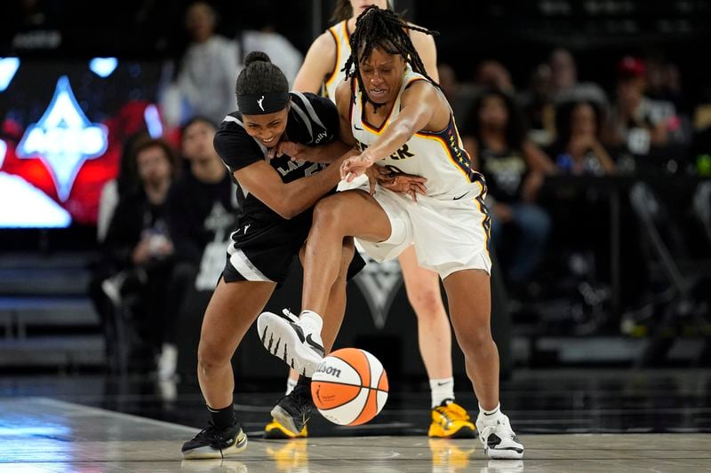 Las Vegas Aces guard Sydney Colson, left, and Indiana Fever guard Kelsey Mitchell battle for the ball during the second half of a WNBA basketball game Saturday, May 25, 2024, in Las Vegas. (AP Photo/John Locher)
