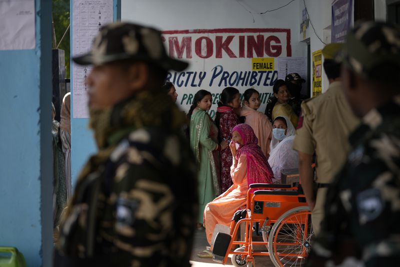 Paramilitary soldiers stand guard as people queue up to vote during the first phase of the Jammu and Kashmir assembly election, in Kishtwar, India, Wednesday, Sept. 18, 2024. (AP Photo/Channi Anand)