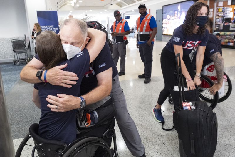 Jim Murdock, medical coordinator for the USA wheelchair rugby team hugs athlete Sarah Adam before boarding a Delta flight in Atlanta on Tuesday, Aug. 20, 2024 as they head to Paris to compete. (Ben Gray / Ben@BenGray.com)