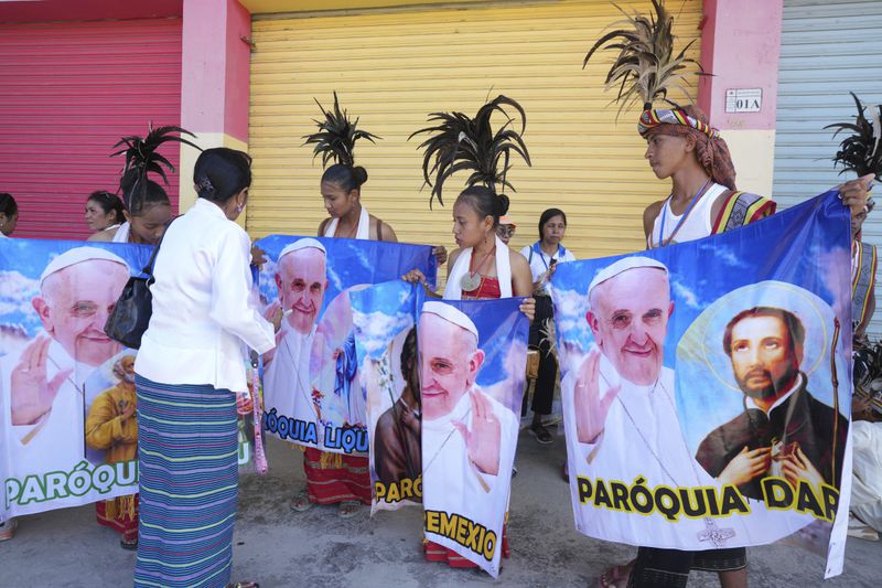 People with traditional dress hold banners of Pope Francis as they prepare to welcome the pope's visit in Dili, East Timor Monday, Sept. 9, 2024. (AP Photo/Firdia Lisnawati)