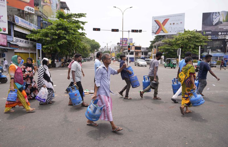 Sri Lankans rush with empty cylinders to buy cooking gas at a distribution centre amid the country's worst economic crisis in recent memory, in Colombo, Sri Lanka, Sunday, May 8, 2022. (AP Photo/Eranga Jayawardena, File)