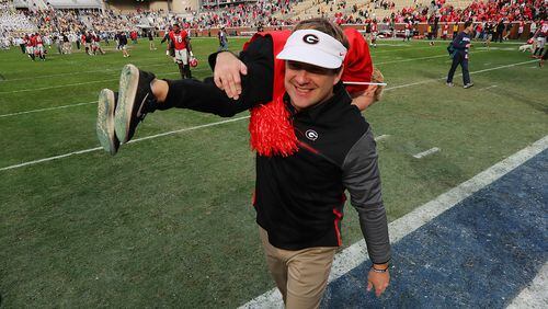 Georgia head coach Kirby Smart walks off the field celebrating with his five-year-old son Andrew after beating Georgia Tech 38-7 on Saturday at Bobby Dodd Stadium.