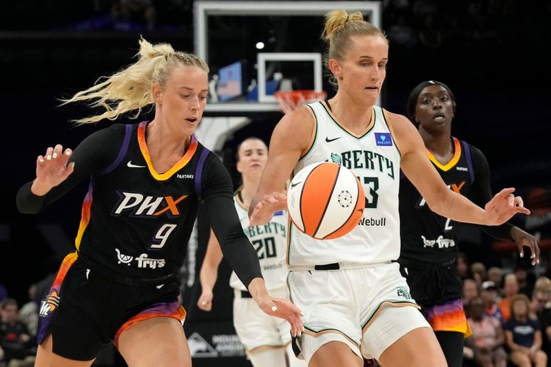 Phoenix Mercury guard Sophie Cunningham (9) tips the ball away from New York Liberty forward Leonie Fiebich, front right, during the first half of WNBA basketball game Monday, Aug. 26, 2024, in Phoenix. (AP Photo/Ross D. Franklin)