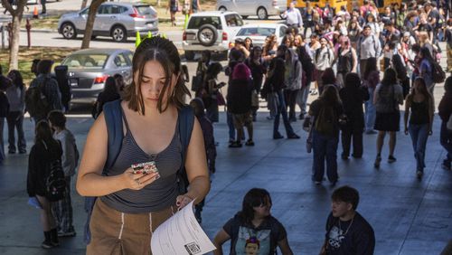 FILE - Student Keiran George uses her cellphone as she steps outside the Ramon C. Cortines School of Visual and Performing Arts High School in downtown Los Angeles on Tuesday, Aug. 13, 2024. (AP Photo/Damian Dovarganes, File)