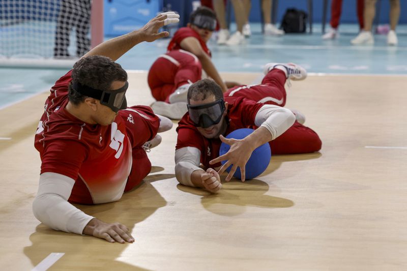 France's Haris Neilmarlija,right, dives in front of teammate Kada Boualia to prevent the ball from going into the goal during the mens' United States versus France goalball game at the Paralympic Games in Paris, Saturday, Aug. 31, 2024. (AP Photo/Felix Scheyer)