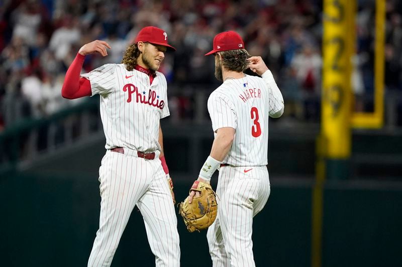 Philadelphia Phillies' Alec Bohm, left, and Bryce Harper (3) celebrate after the Phillies won a baseball game against the Chicago Cubs to clinch the NL East title, Monday, Sept. 23, 2024, in Philadelphia. (AP Photo/Matt Slocum)