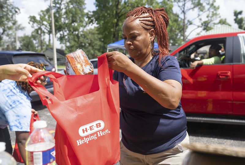 Debra McCarty with Harris County Precent 1 works to distribute food at Lincoln Park in Houston, on Wednesday, July 10, 2024. (Elizabeth Conley/Houston Chronicle via AP)
